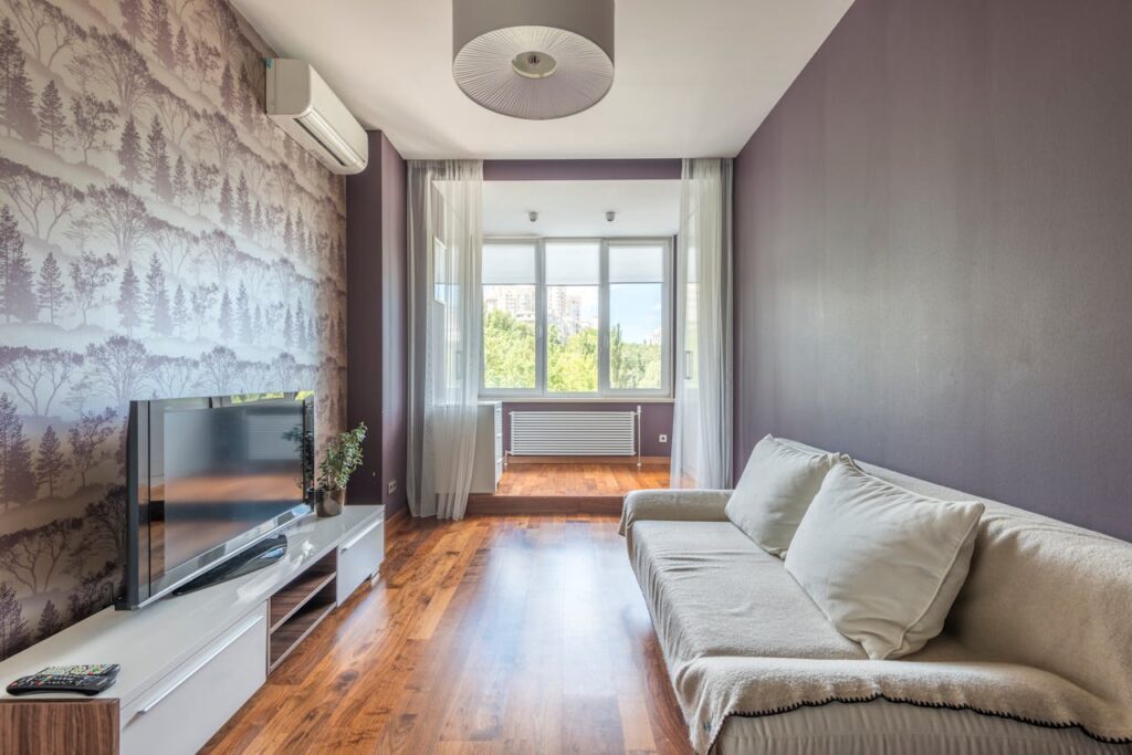 pexels photo 8089160 Spacious modern living room featuring air conditioning, a sofa, and large windows with natural light.